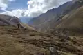 Wanderer auf einem Bergpfad in einem Gebirgstal.