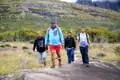 Vier Wanderer auf einem felsigen Wanderweg in den Hügeln.