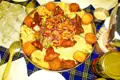 Gebratenes Hühnchen mit Salat und Beilagen auf einer Platte.