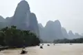 Traditionelle Boote fahren auf einem Fluss, umgeben von den charakteristischen Karstbergen.