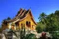 Traditionelle laotische Tempelarchitektur mit vergoldeten Verzierungen und umgeben von Palmen.