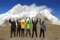 Wandergruppe feiert den erfolgreichen Aufstieg mit Gebetsfahnen vor dem Himalaya-Gebirge.