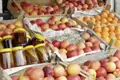 Auslage mit Äpfeln, Orangen und Honiggläsern auf einem Markt.
