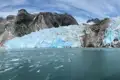Kalbender Gletscher mit blauem Eis und umliegenden Bergen.