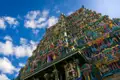 Bunter Tempel mit vielen Details und Figuren vor einem blauen Himmel mit Wolken.