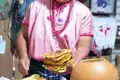 Frau in traditioneller Kleidung präsentiert einen Stapel frisch zubereiteter Tortillas.