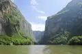 Flussfahrt durch eine Schlucht mit hohen, bewaldeten Wänden.