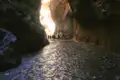 Wanderer durchqueren eine wasserführende Schlucht.