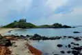 Traditionelles Gebäude auf einer Insel, felsiger Strand, bewölkter Himmel