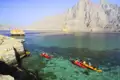 Kajaks im türkisfarbenen Wasser, umgeben von felsigen Klippen und Bergen.