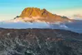 Goldener Berggipfel in der Abendsonne mit Wolkenformationen.