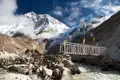 Holzbrücke mit Gebetsfahnen im Himalaya Gebirge.