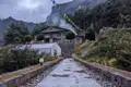 Weg zu einer Berghütte im Himalaya mit Gebetsfahnen und einem Gewächshaus.