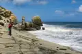 Radfahrer am Strand mit Felsformationen im Hintergrund.