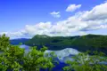 Panoramablick auf einen ruhigen See und grüne Hügel.