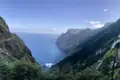 Wanderweg entlang der Küste mit Blick auf das blaue Meer und die bewachsenen Klippen.