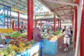 Marktstände mit tropischen Früchten und Gemüse, besucht von Einheimischen.