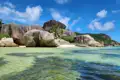 Granitfelsen und türkisfarbenes Wasser an einem tropischen Strand.