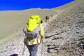 Wanderer mit Rucksäcken auf einem steinigen Bergpfad.