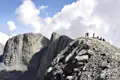 Wanderer auf einem Berggipfel mit Blick auf die umliegenden Berge.