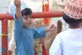 Zwei Kinder in traditioneller Kleidung beobachten Ziegen auf einem Bauernhof oder Markt.