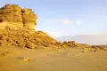 Eine markante Felsformation in einer sandigen Wüstenlandschaft.