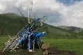 Gebetsstätte mit blauen Gebetsfahnen und einem Stein in der Vordergrund, im Hintergrund eine bewaldete Berglandschaft.