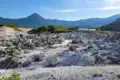 Vulkanische Gesteinsformationen mit Bergen und See im Hintergrund.