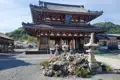 Eingangstor eines japanischen Tempels mit traditionellen Steinlaternen und einem Steinhaufen im Vordergrund.