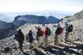 Wanderer mit Rucksäcken und Wanderstöcken betrachten die Berglandschaft von einem Gipfel aus.