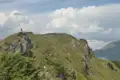 Wanderer auf einem Berggipfel mit Blick auf die umliegenden Berge und Täler.