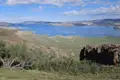 Panoramablick auf einen See mit Hügeln und Vegetation.