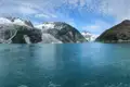 Panoramablick auf einen Gletscher, der in einen türkisfarbenen See mündet, umgeben von schneebedeckten Bergen.