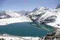 Türkisfarbener See inmitten schneebedeckter Berge.