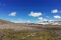 Wanderer in einer hochgelegenen Landschaft mit schneebedeckten Bergen im Hintergrund.