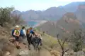 Wandergruppe pausiert auf einem Bergpfad und betrachtet die Landschaft mit Schlucht und Stausee.