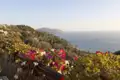 Panoramablick auf die Küste vom Balkon aus, mit Blick auf das Meer und bewachsene Hügel.