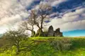 Historische Burgruine inmitten einer grünen Landschaft.