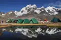 Basislager in den Bergen mit Zelten und einem kleinen See.