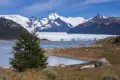 Panoramablick auf einen Gletscher, der in einen See kalbt, mit imposanten Bergen im Hintergrund.