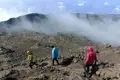Wanderer auf einem vulkanischen Pfad. Nebel bedeckt den Gipfel des Vulkans im Hintergrund.