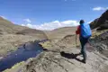 Wanderer auf einem Bergpfad neben einem Fluss.