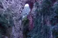 Natürlicher Felsbogen in einer Schlucht, bewachsen mit Vegetation.