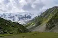 Basislager mit Zelten inmitten einer Hochgebirgslandschaft mit Gletscher und schneebedecktem Berg.