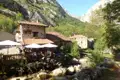 Restaurant in einem Bergdorf, umgeben von Bergen und einem Fluss.