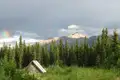 Hütte am Waldrand mit Blick auf die Berge und einen Regenbogen.