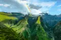 Panoramablick auf eine Bergkette mit einem Regenbogen.