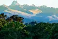 Panoramablick auf den Mount Kenya mit Bäumen im Vordergrund.