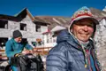 Lächelnder Bergführer während einer Trekkingtour in den Bergen. Im Hintergrund eine Berghütte.