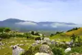 Panoramablick auf eine Berglandschaft mit Tal und Wolken.